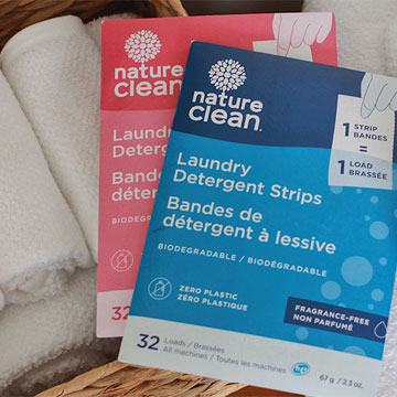 Produits Nature Clean dans un panier à linge avec des serviettes blanches