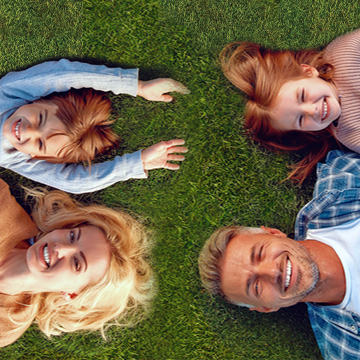 family of 4 laying on grass