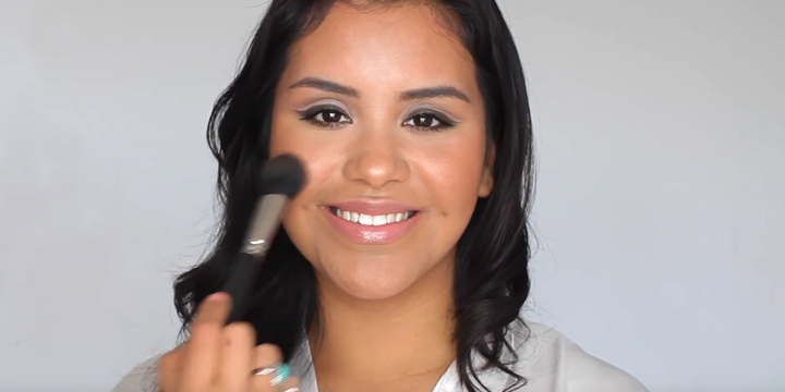 woman holding a brush to her cheeks and smiling