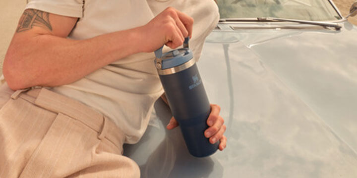 a guy holding stanely bottle on the car