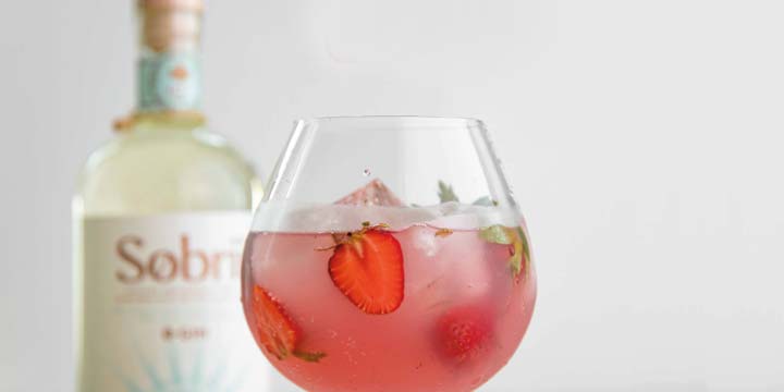 bottle of sobrii non-alcoholic spirit and glass of spirit with strawberries