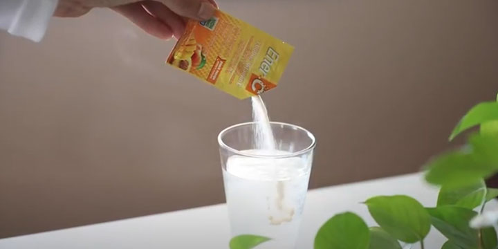 person pouring Ener-C product in glass of water