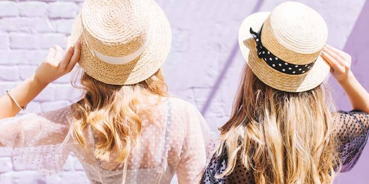 the back of two women's heads wearing summer hats