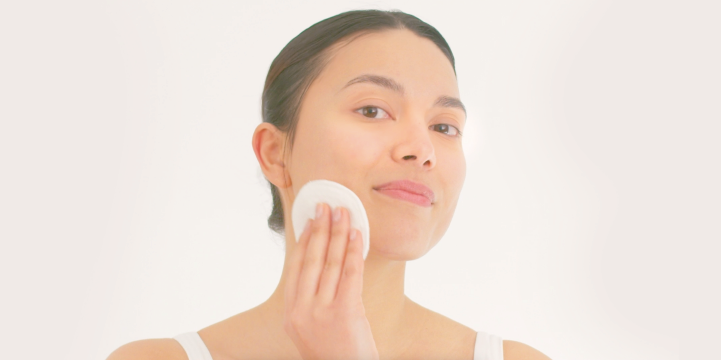 woman with cotton pad cleansing her face