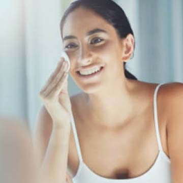 woman smiling applying product to her face