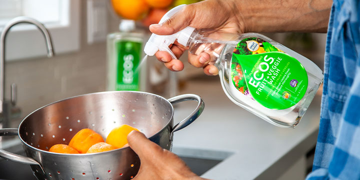 man standing at sink and spraying ECOS fruit spray on a bowl of fruit