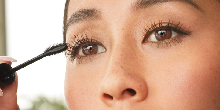 woman looking back holding a tube of bareminerals mascara