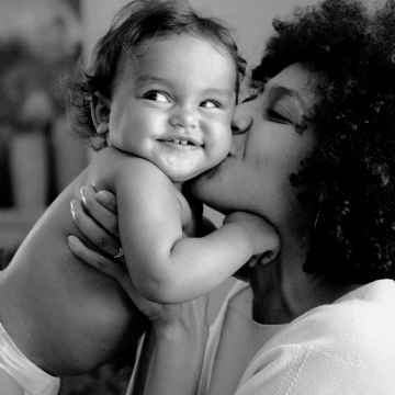 mother holding baby and kissing their cheek