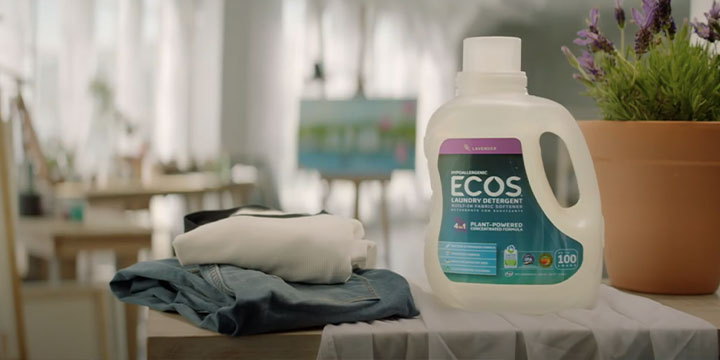 ECOS laundry detergent in the middle of a pile of clothes and a plant